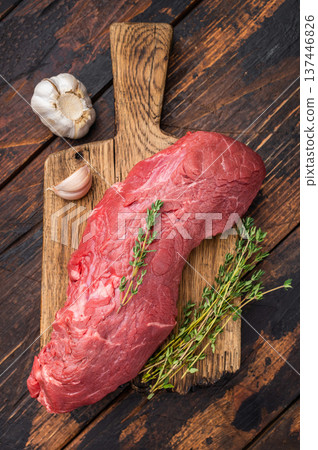 Uncooked beef fillet with herbs and garlic on wooden background. Premium ingredient suitable for oven roast beef or tenderloin recipes. Uncooked beef fillet with herbs and garlic on wooden background. Premium ingredient suitable for oven roast beef or tenderloin recipes. 137446826