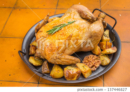Homemade roast chicken with potatoes baked in pan. Traditional comfort food on warm yellow background, overhead food photography Homemade roast chicken with potatoes baked in pan. Traditional comfort food on warm yellow background, overhead food photography 137446827
