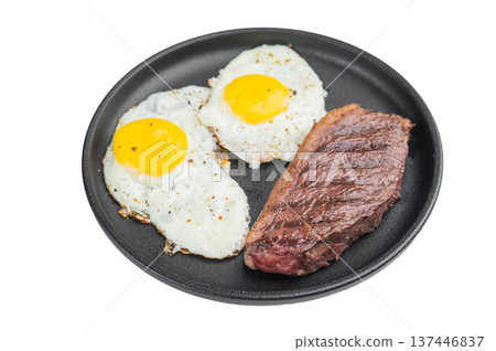Classic American steak and eggs with beef steak and two sunny side fried eggs cooked in cast iron skillet on isolated background Classic American steak and eggs with beef steak and two sunny side fried eggs cooked in cast iron skillet on isolated background 137446837