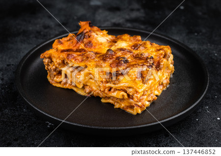 Classic Italian lasagna with beef meat sauce pasta layers and melted cheese on black plate overhead copy space Classic Italian lasagna with beef meat sauce pasta layers and melted cheese on black plate overhead copy space 137446852