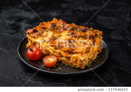 Classic Italian lasagne al forno with beef meat sauce pasta layers and melted cheese on dark plate Classic Italian lasagne al forno with beef meat sauce pasta layers and melted cheese on dark plate 137446855