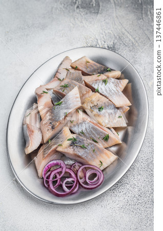 Salted and marinated herring pieces with red onion and thyme served in white dish on wooden board. Light stone background with copy space. Salted and marinated herring pieces with red onion and thyme served in white dish on wooden board. Light stone background with copy space. 137446861