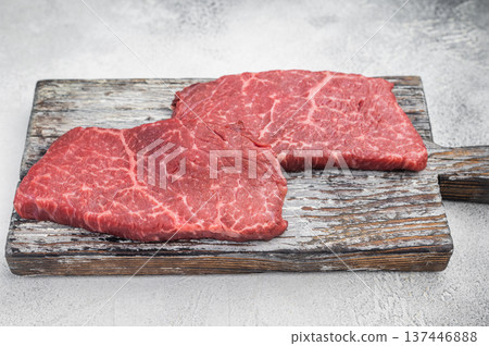 Uncooked chuck flatiron beef steaks with thyme sprigs and seasoning on vintage board overhead minimal composition Uncooked chuck flatiron beef steaks with thyme sprigs and seasoning on vintage board overhead minimal composition 137446888