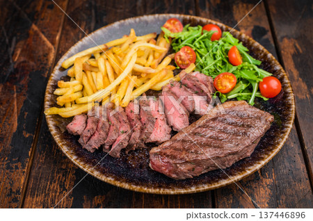 Sliced and whole picanha or top sirloin cap steak with french fries and fresh arugula salad served on plate, top view on rustic wooden table Sliced and whole picanha or top sirloin cap steak with french fries and fresh arugula salad served on plate, top view on rustic wooden table 137446896
