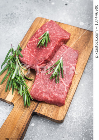Raw marbled wagyu top side beef cut with rosemary and salt on wooden board. Premium red meat top view with copy space. Raw marbled wagyu top side beef cut with rosemary and salt on wooden board. Premium red meat top view with copy space. 137446900
