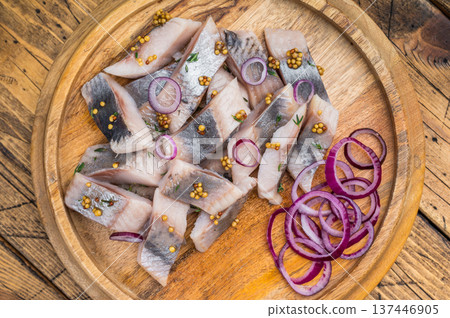 Pickled herring chunks cured in salt and brine served with onion and mustard. Traditional seafood appetizer on rustic wood. 137446905