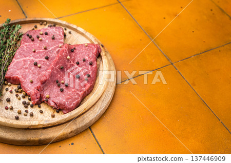 Uncooked marbled top blade beef steaks with rosemary thyme and peppercorn seasoning on wooden board top view copy space Uncooked marbled top blade beef steaks with rosemary thyme and peppercorn seasoning on wooden board top view copy space 137446909