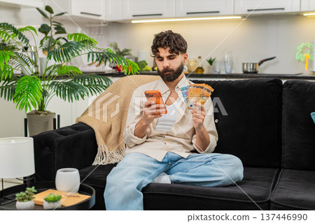 Indian man counting euro money cash salary using smartphone calculator for vacation budget future 137446990