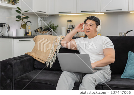 Asian man types on laptop with soft music focused workflow calm mood keeps pace and finishes tasks 137447006