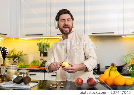Middle-aged man peeling fresh apple in home kitchen for healthy diet nutrition wellbeing lifestyle Middle-aged man peeling fresh apple in home kitchen for healthy diet nutrition wellbeing lifestyle 137447043