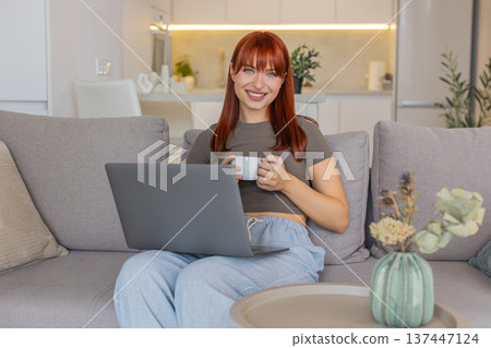 Young woman with coffee cup checks email on laptop works freelance remote tasks client inbox replies 137447124