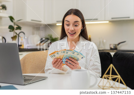 Young woman counts cash euros smiles satisfied high salary savings plans invest money finance goal 137447133