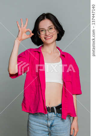 Young woman smiling nodding showing okay gesture with fingers positive approval agreement reaction 137447140