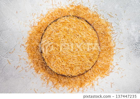Kadaif pastry dough with fine crispy strands in wooden bowl. Baking ingredient flatlay on dark concrete background Kadaif pastry dough with fine crispy strands in wooden bowl. Baking ingredient flatlay on dark concrete background 137447235