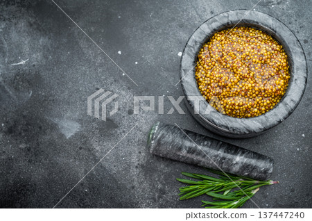 Traditional Dijon mustard with rich grainy texture prepared in stone mortar rustic food styling on dark background Traditional Dijon mustard with rich grainy texture prepared in stone mortar rustic food styling on dark background 137447240