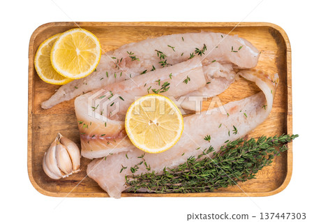 Raw Pollock and Hake fish fillets on a wooden board with herbs ready for cooking isolated on white background. top view 137447303