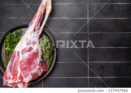 Uncooked whole lamb leg, raw mutton meat with herbs for cooking. black background. top view 137447466