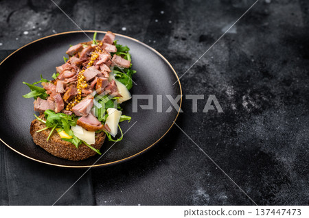 Toast with duck breast meat, foie gra, arugula and cheese on plate. black background. top view Toast with duck breast meat, foie gra, arugula and cheese on plate. black background. top view 137447473