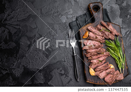 Roast Skirt Machete Steak, grilled beef meat on cutting board. black background. top view Roast Skirt Machete Steak, grilled beef meat on cutting board. black background. top view 137447535