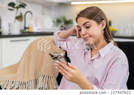Young woman tired from news feed sets smartphone aside closes eyes exhales seeking break from screen Young woman tired from news feed sets smartphone aside closes eyes exhales seeking break from screen 137447622