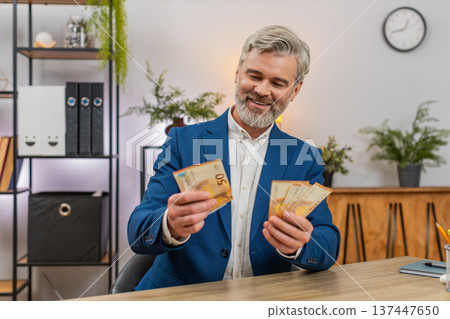 Middle-aged businessman holding euro cash counting salary income celebrating big success happiness 137447650