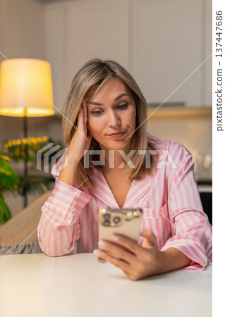 Adult woman scrolls news on smartphone bored tired stressed demotivated seeks calm break at night Adult woman scrolls news on smartphone bored tired stressed demotivated seeks calm break at night 137447686