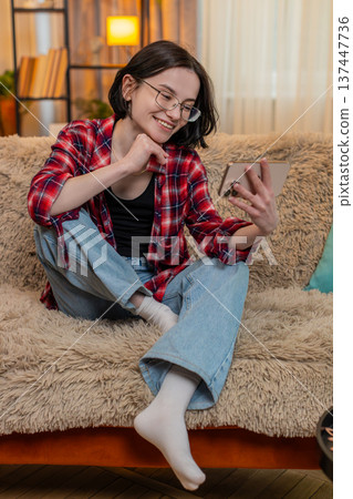 Young woman laughing while listening to podcast on smartphone reacting joyfully funny conversation 137447736