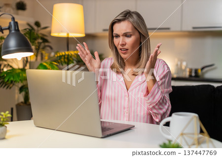 Adult woman freelancer reads tender loss message on laptop frowns shakes head sighs disappointment Adult woman freelancer reads tender loss message on laptop frowns shakes head sighs disappointment 137447769