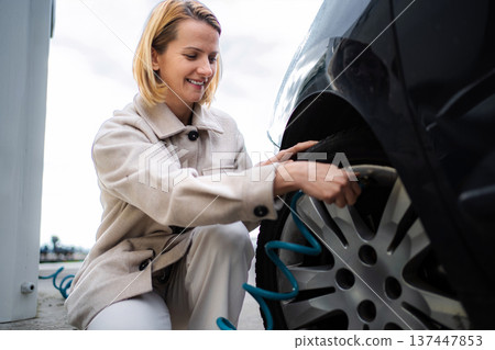 Woman inflating car tire at self service gas station 137447853