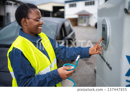 Woman charging electric car at self-service station Woman charging electric car at self-service station 137447855