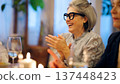 Senior woman laughing and clapping at dinner party 137448423