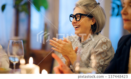 Senior woman laughing and clapping at dinner party 137448423