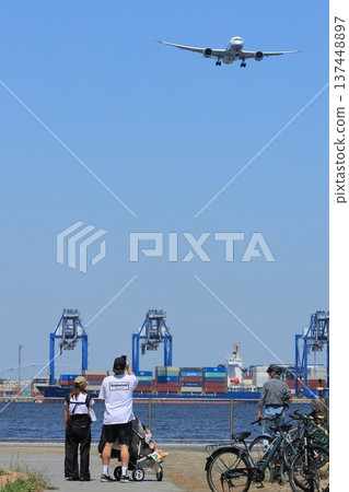 Family taking photos of a landing plane 137448897