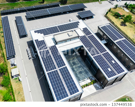 Aerial view of building with solar panels on a roof and parking space with solar canopies. Aerial view of building with solar panels on a roof and parking space with solar canopies. 137449538