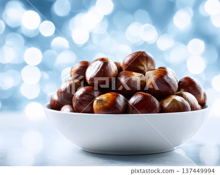 Fresh chestnuts in a white bowl with a blurred blue background creating a cozy atmosphere 137449994