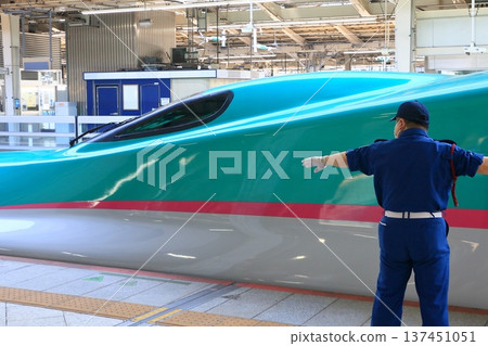 一名保全人員在月台上指揮東北新幹線列車的發車。 一名保全人員在月台上指揮東北新幹線列車的發車。 137451051