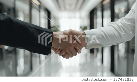 Two Professional Men Engaging in a Firm Handshake in a Brightly Lit Office Hallway 137451832