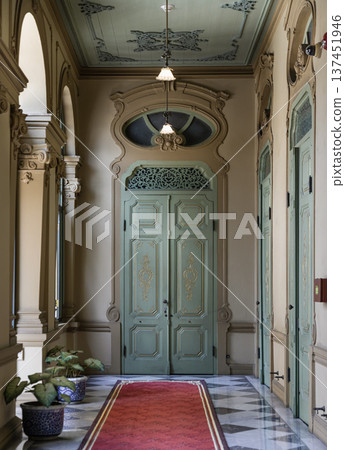 An ornate hallway in Bang Khun Phrom Palace featuring European-influenced architectural details. The design centers on a pale mint green double door with intricate carvings and an oval transom. An ornate hallway in Bang Khun Phrom Palace featuring European-influenced architectural details. The design centers on a pale mint green double door with intricate carvings and an oval transom. 137451946