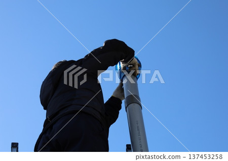 A man climbing a ladder to inspect and clean the roof and gutters (home maintenance) A man climbing a ladder to inspect and clean the roof and gutters (home maintenance) 137453258