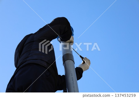 A man climbing a ladder to inspect and repair gutters on a house (home maintenance/working at height) A man climbing a ladder to inspect and repair gutters on a house (home maintenance/working at height) 137453259