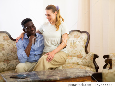 Happy couple in love embracing while sitting on vintage sofa indoors 137453378