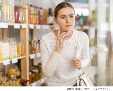 Young woman near the shelves in the supermarket 137453379