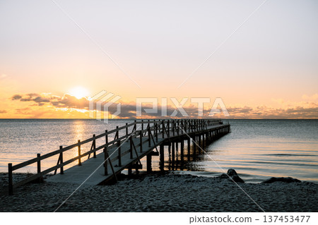 Baltic Sea pier at sunset with golden light reflecting on calm water Baltic Sea pier at sunset with golden light reflecting on calm water 137453477