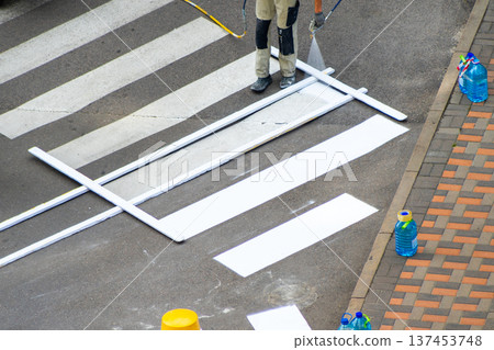 Road Worker Painting Pedestrian Crossing. Applying markings. Paint spray white color line. Highway crosswalk mark working man Road Worker Painting Pedestrian Crossing. Applying markings. Paint spray white color line. Highway crosswalk mark working man 137453748