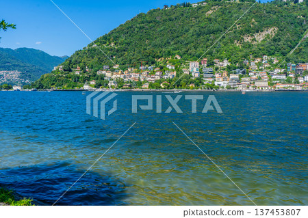 Como lake water in Summer day. Multicolor houses on green mountains Italian travel. Italy. 137453807