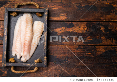 Fresh fish meat, Raw cod loin pieces without skin in wooden tray. wooden background. top view Fresh fish meat, Raw cod loin pieces without skin in wooden tray. wooden background. top view 137454330