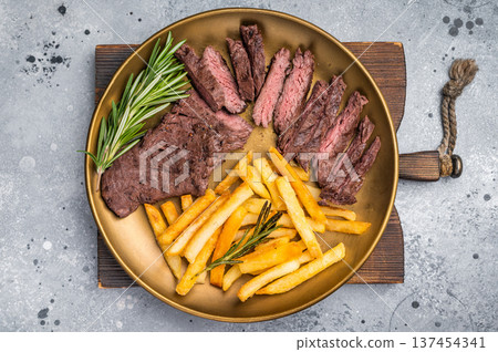 BBQ Grilled Beef Skirt Machete Steak on a plate with french fries grey background. top view BBQ Grilled Beef Skirt Machete Steak on a plate with french fries grey background. top view 137454341
