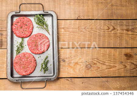 Raw hamburger minced meat patties for burgers with herbs on tray. wooden background. top view 137454346