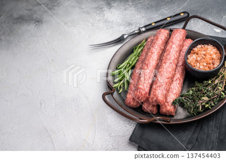 Raw Cevapcici ready for the grill, fresh Cevapi from mince beef meat. grey background. top view Raw Cevapcici ready for the grill, fresh Cevapi from mince beef meat. grey background. top view 137454403