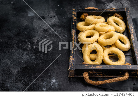 Raw squid rings with breading, uncooked calamari snack. black background. top view Raw squid rings with breading, uncooked calamari snack. black background. top view 137454405